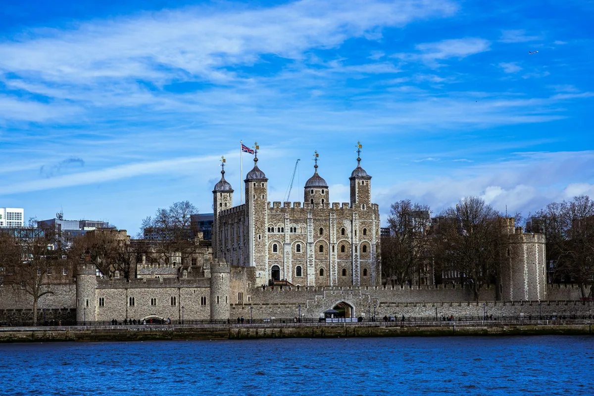 Tower of London med White Tower og ringmurene, sett over Themsen under blå himmel