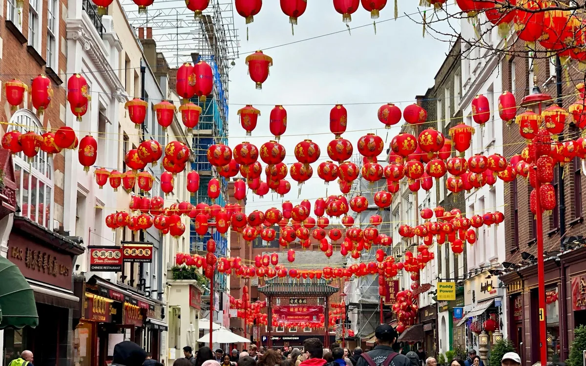 Hundrevis av røde lykter over en gate i Chinatown, med kinesiske restauranter og en portal i enden av gaten