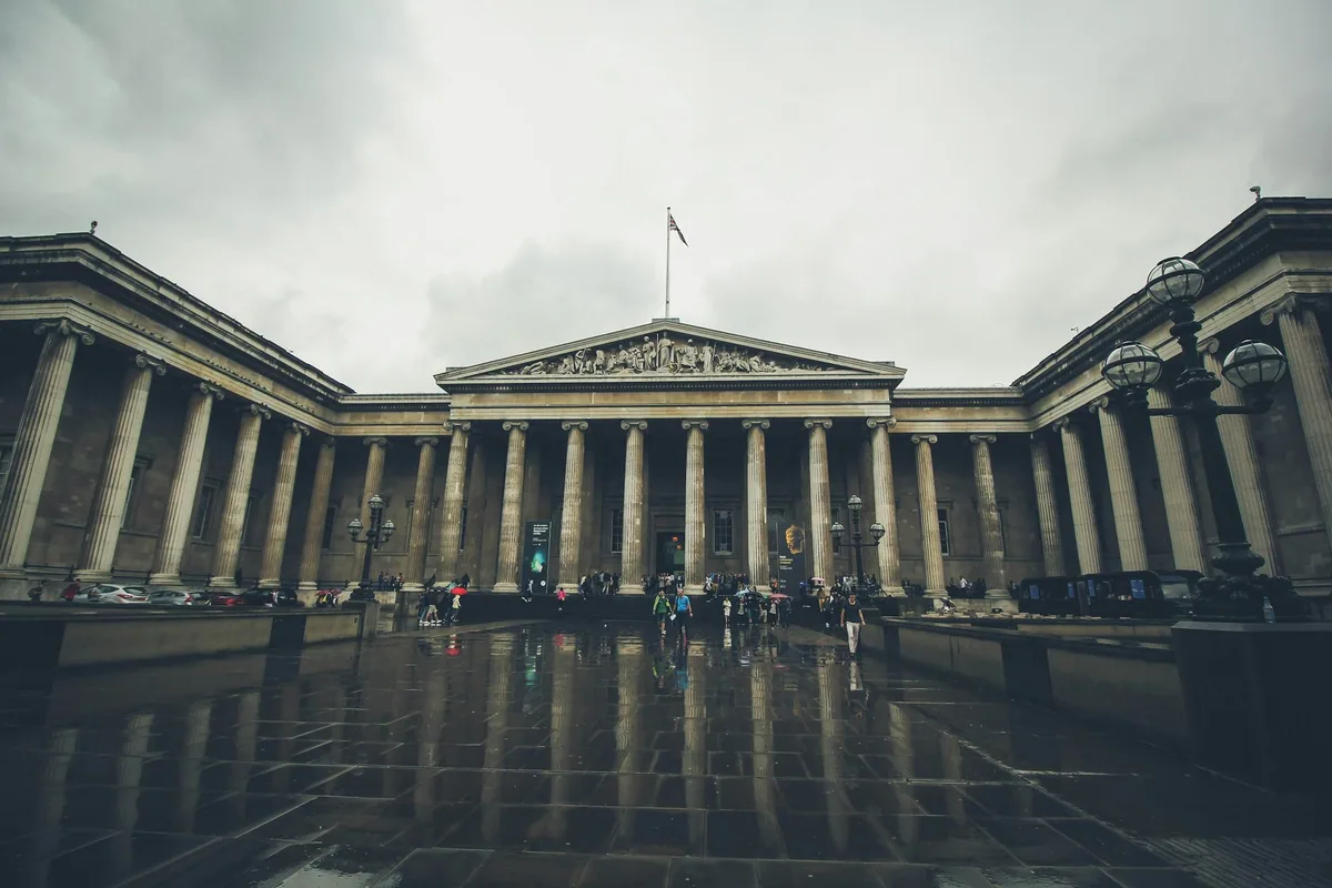 Søylefasaden til British Museum en regnværsdag, speilet i den våte forplassen