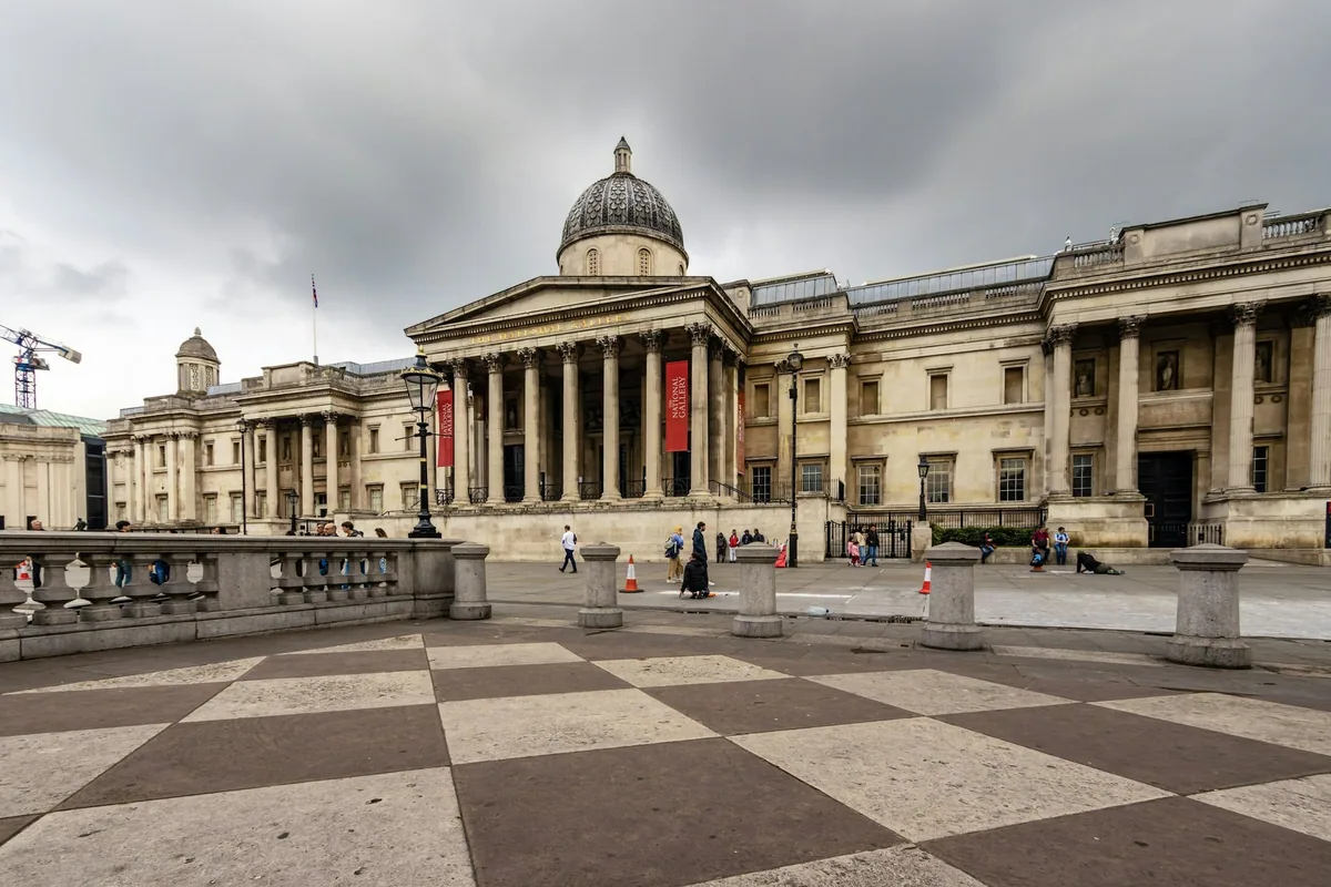 Fasaden til National Gallery med søylerad og kuppel, sett fra terrassen på Trafalgar Square en overskyet dag