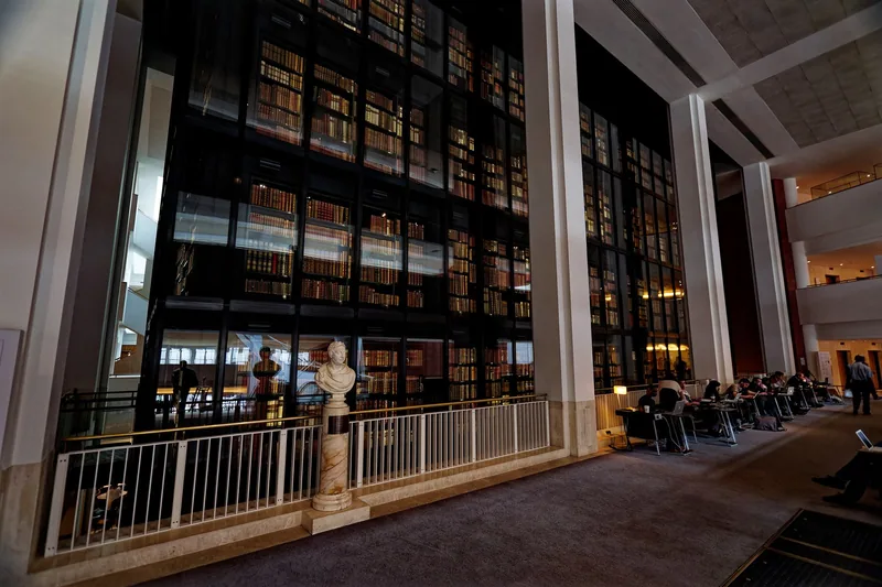 King's Library i British Library, et høyt glasstårn fullt av gamle bøker, med lesende ved bordene ved siden av