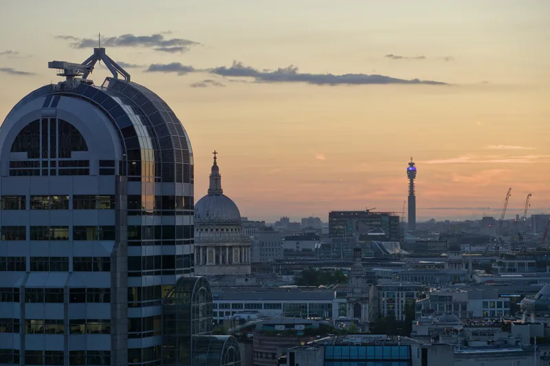 Utsikt fra takhagen mot kuppelen på St Paul's Cathedral og BT Tower i solnedgang, med en kontorblokk i City til venstre