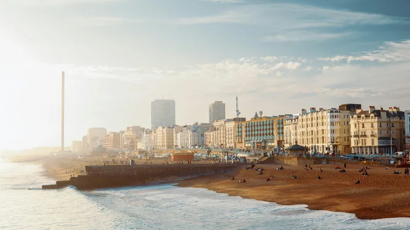 Strandpromenaden i Brighton med stranden, hotellfasadene og i360-tårnet, sett fra piren i ettermiddagslys