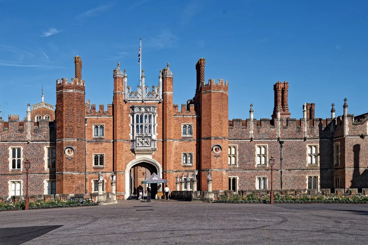 Tudor-porthuset i rød tegl på vestfasaden av Hampton Court Palace under blå himmel