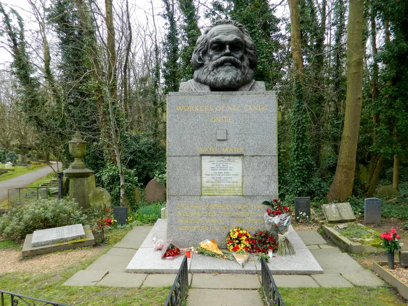 Karl Marx' grav på Highgate Cemetery med bronsebyste på en granittsokkel og blomster lagt ved foten