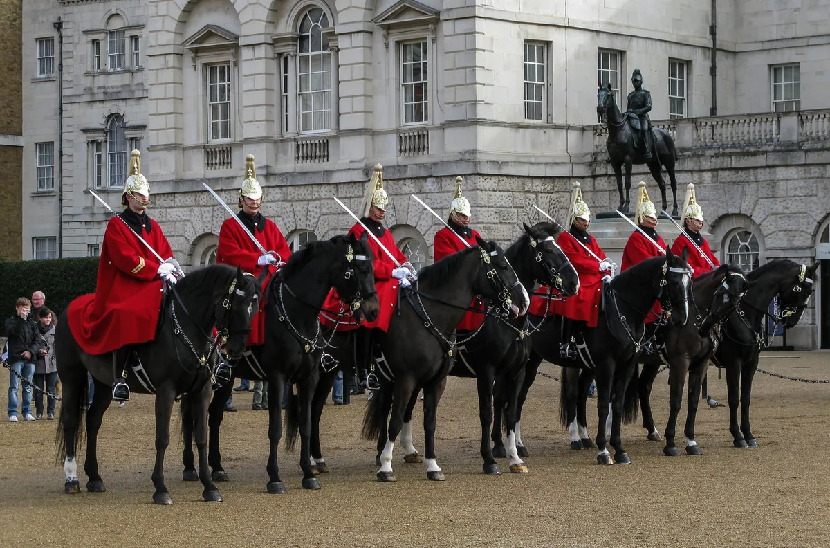 Ryttere fra Household Cavalry i røde uniformer og blanke hjelmer på svarte hester på Horse Guards