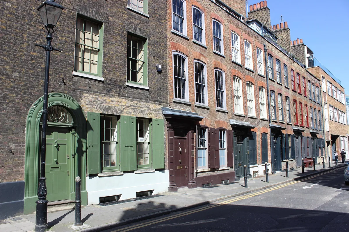 Georgianske rekkehus i mørk murstein med skodder og gatelykt i Wilkes Street i Spitalfields