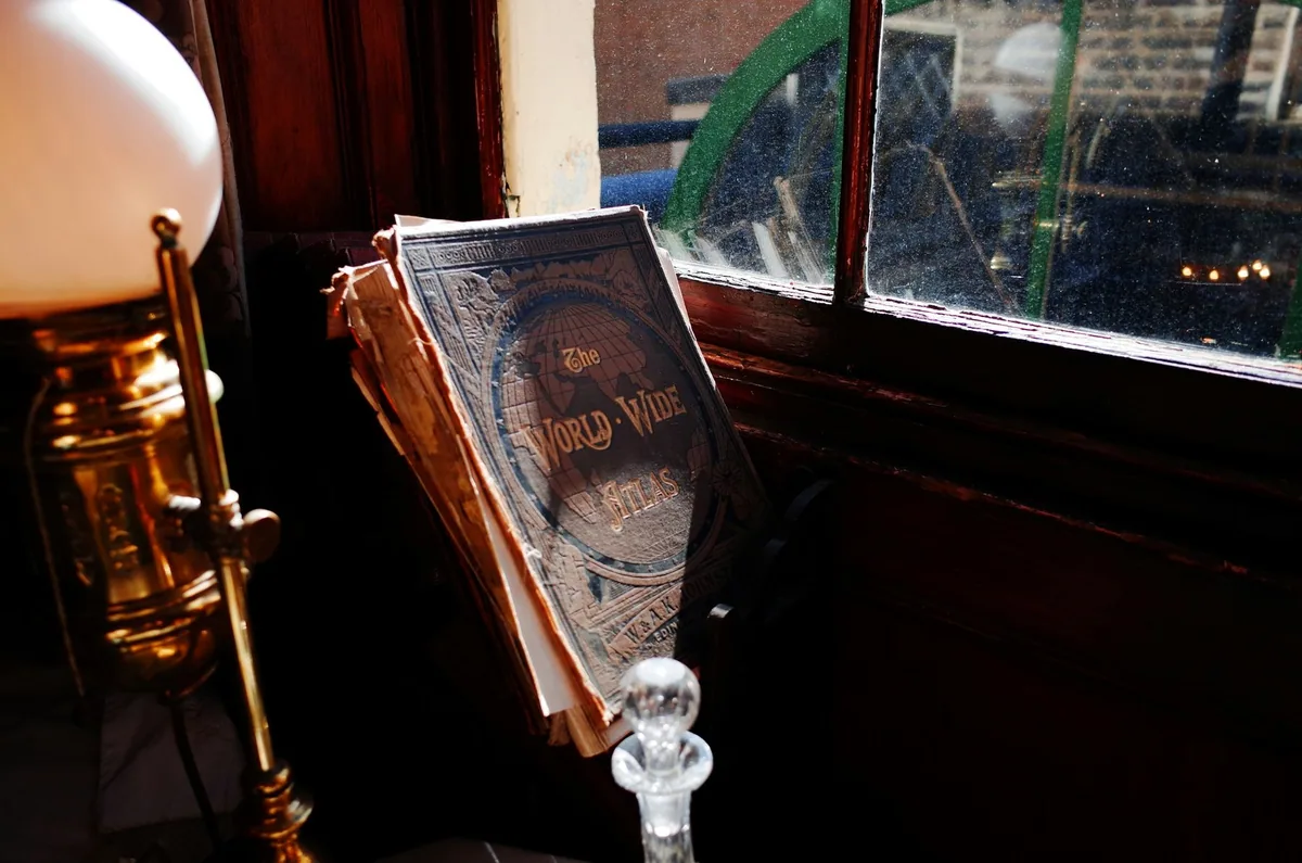 Et slitt viktoriansk verdensatlas og en messinglampe i vinduskarmen i Dr. Watsons rom i Sherlock Holmes Museum