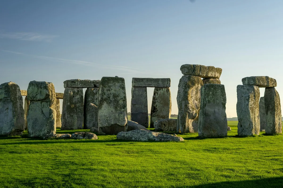 Steinringen Stonehenge i lavt kveldslys, med grønt gress og klar himmel