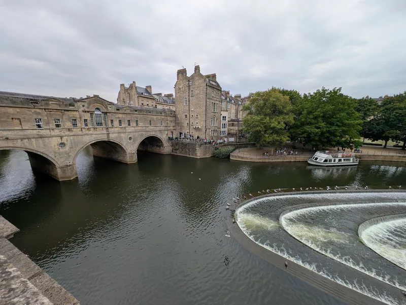 Pulteney Bridge over elva Avon i Bath, med den buede demningen i forgrunnen