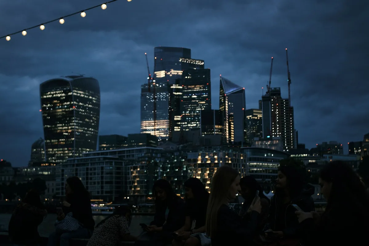 De opplyste skyskraperne i City of London, med Walkie-Talkie til venstre, under en mørk og skyet kveldshimmel