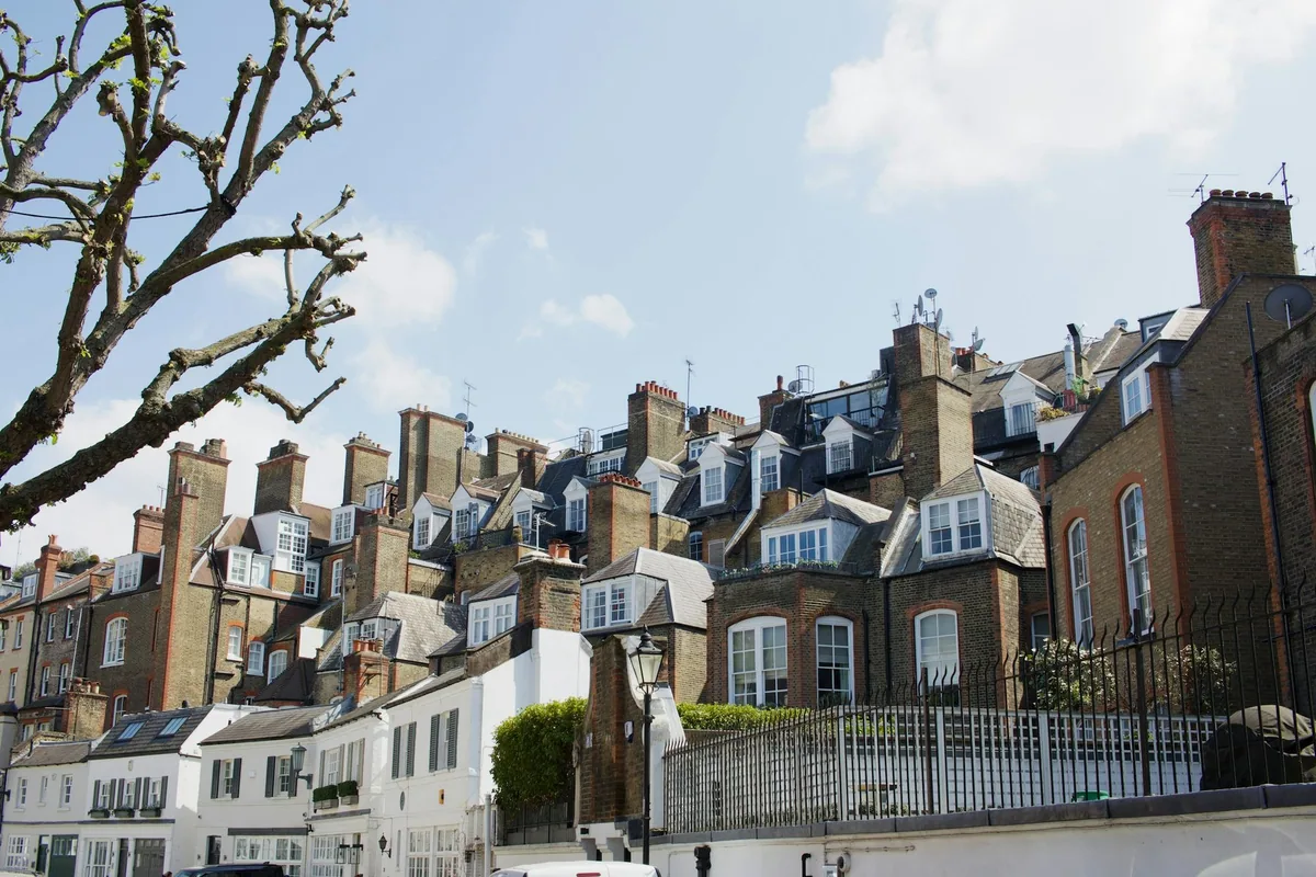Tette rekker av murhus med takvinduer og skorsteiner i et boligstrøk i London en solfylt dag