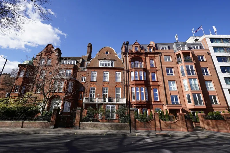 Viktorianske bygårder i rød mur langs en gate i Kensington under blå himmel