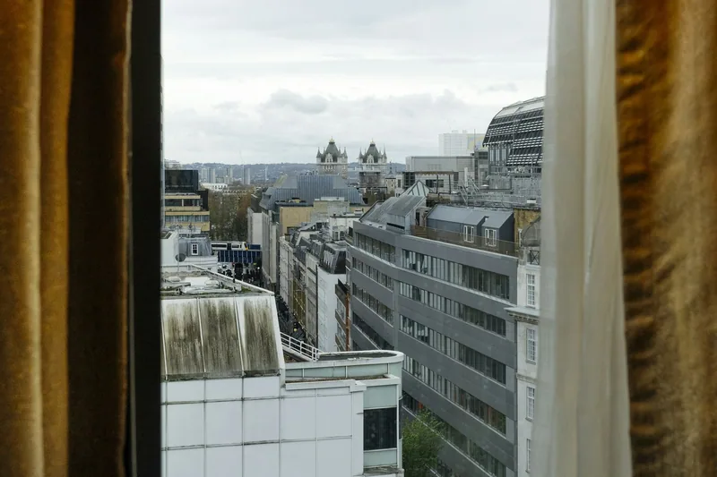 Utsikt fra et hotellvindu i London over takene mot tårnene på Tower Bridge en grå dag