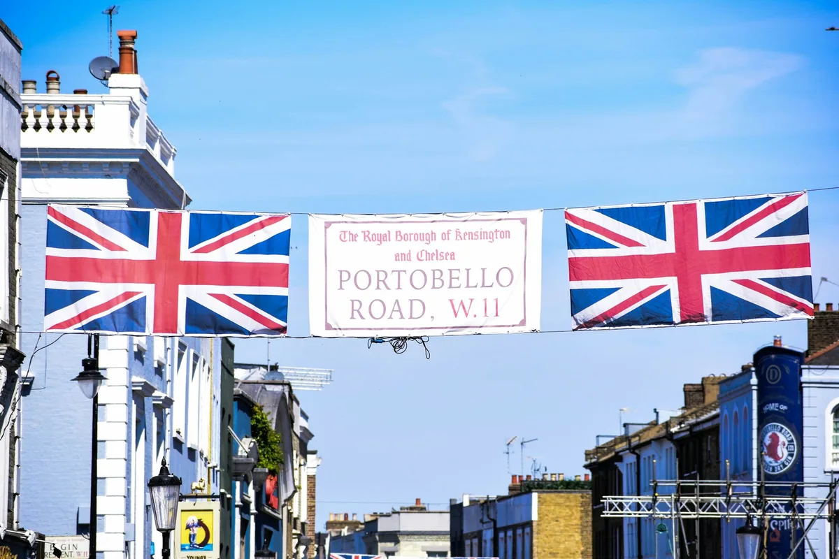 Union Jack-flagg og bydelens banner over Portobello Road i Notting Hill en solrik dag