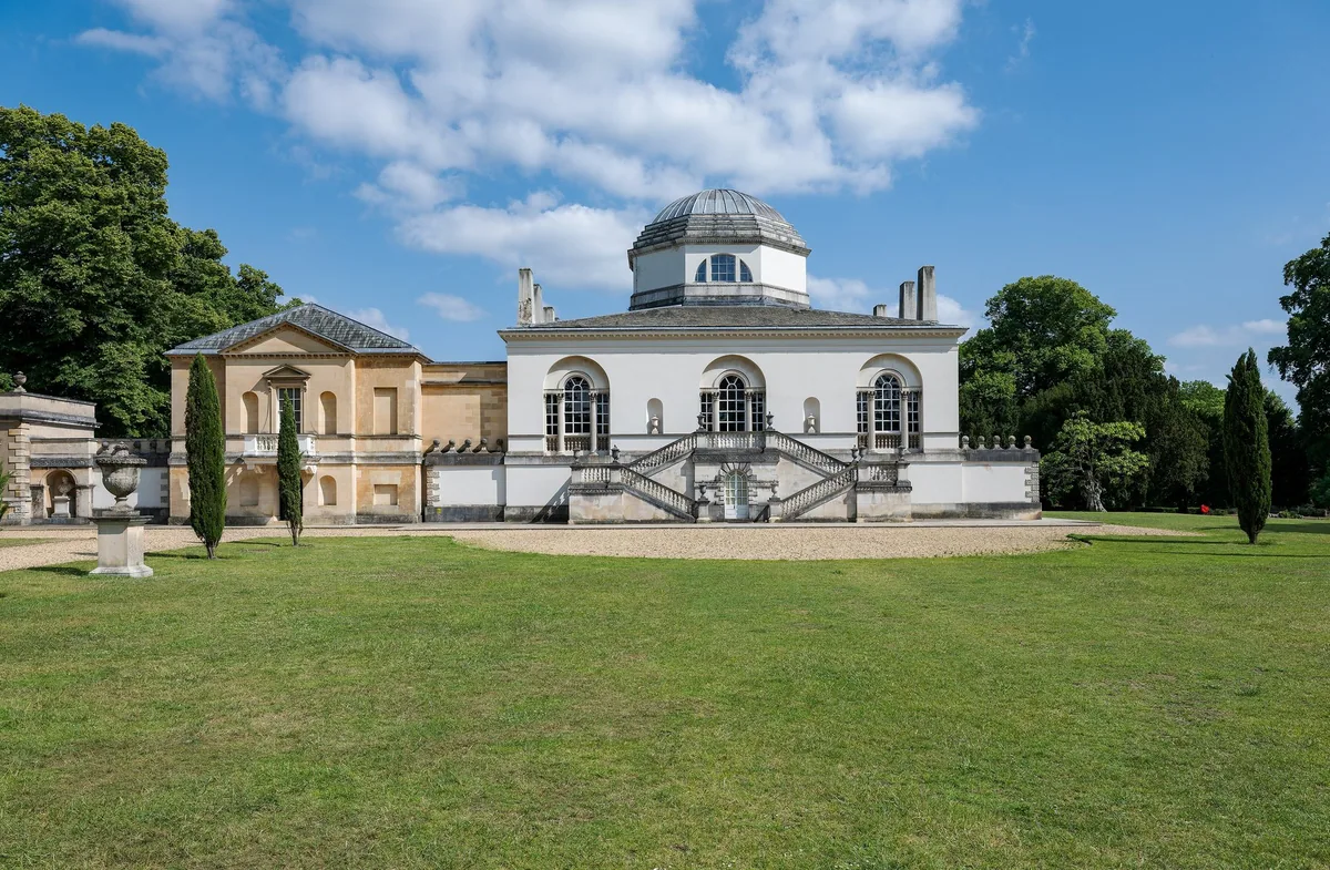 Chiswick House, en hvit villa med kuppel og doble trapper, bak en stor gressplen en sommerdag