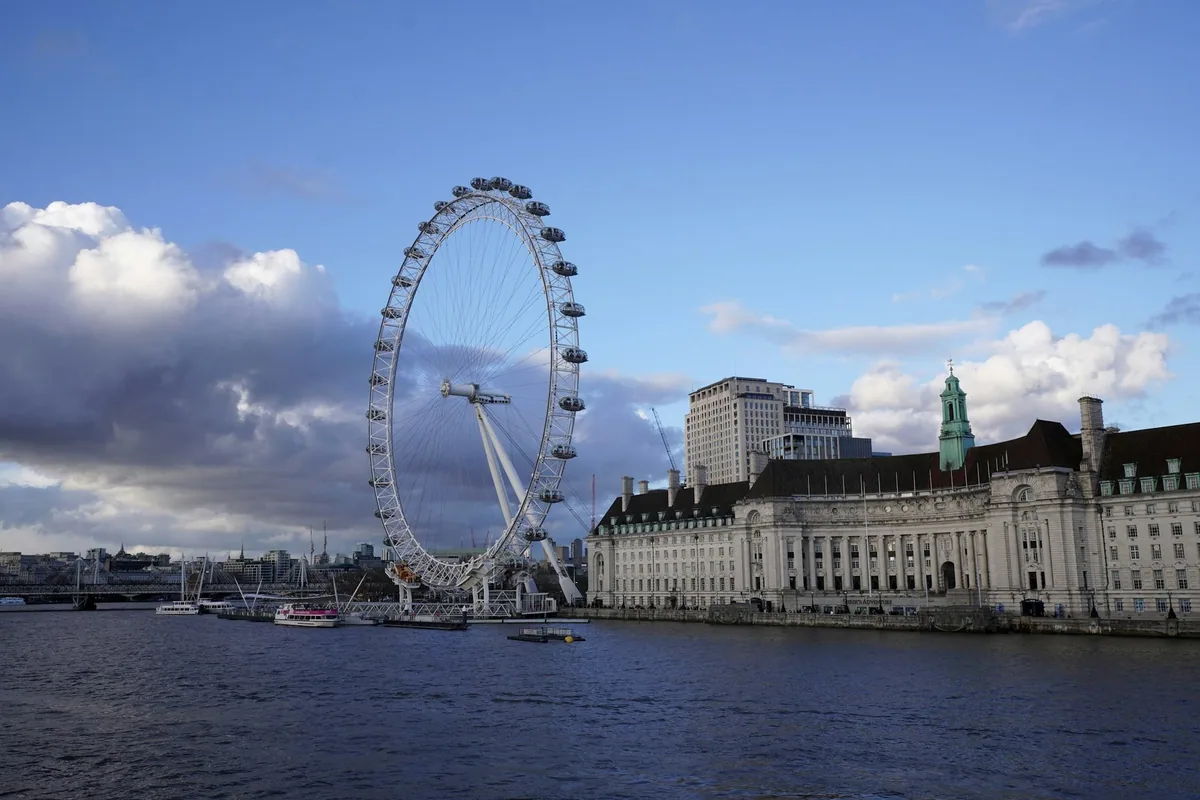 London Eye og County Hall ved Themsen på South Bank under blå himmel med mørke skyer