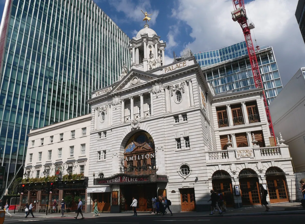 Den hvite fasaden på Victoria Palace Theatre i Victoria Street, med moderne glassbygg på begge sider