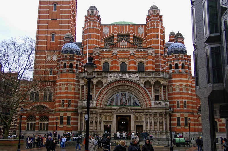 Den stripete fasaden i rød tegl og hvit stein på Westminster Cathedral, med folk på plassen foran