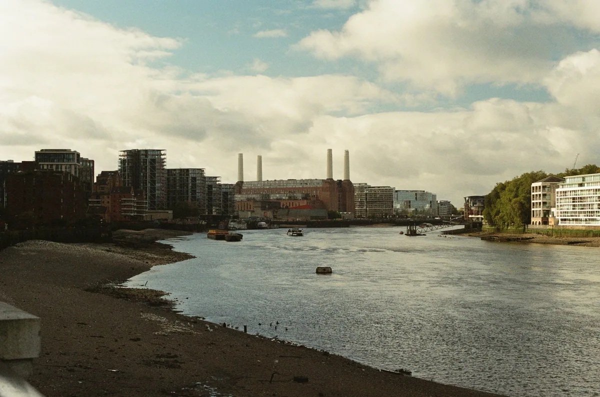 Battersea Power Station med de fire hvite skorsteinene, sett langs Themsen ved lavvann