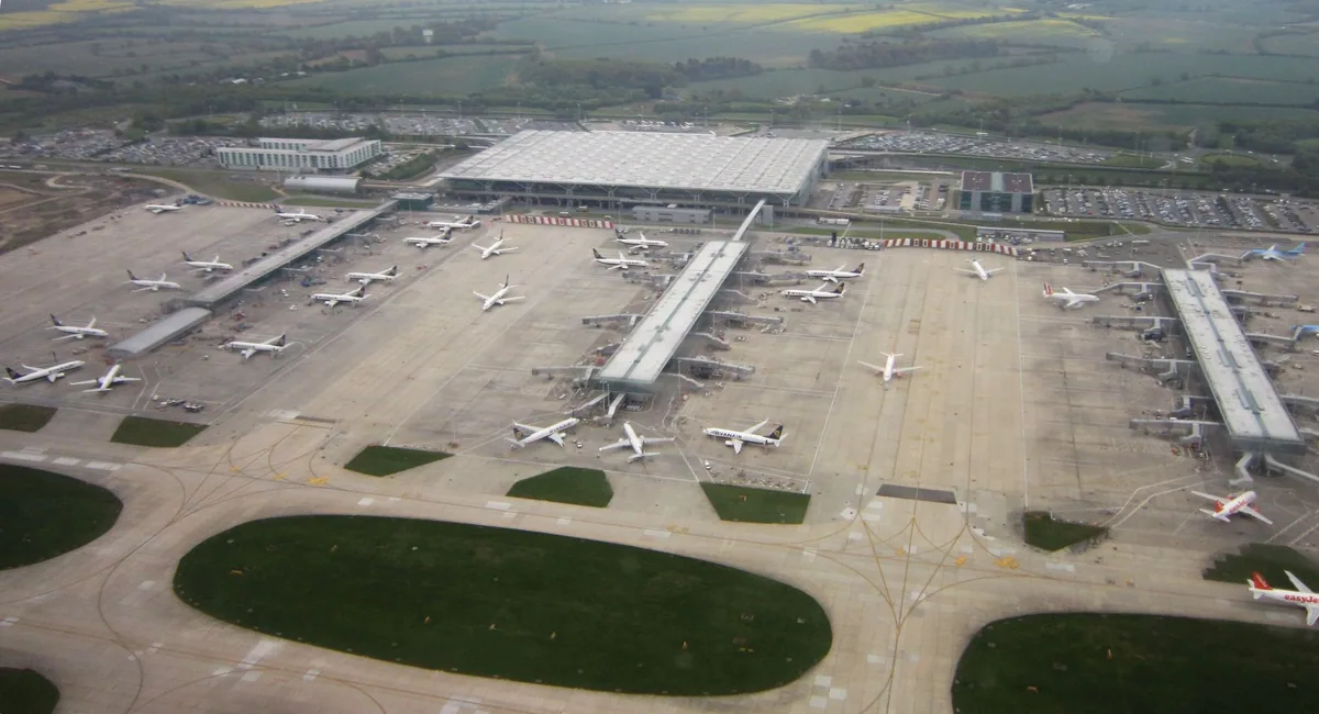 Stansted Airport sett fra lufta, med hovedterminalen, tre satellittbygg og fly parkert ved gatene