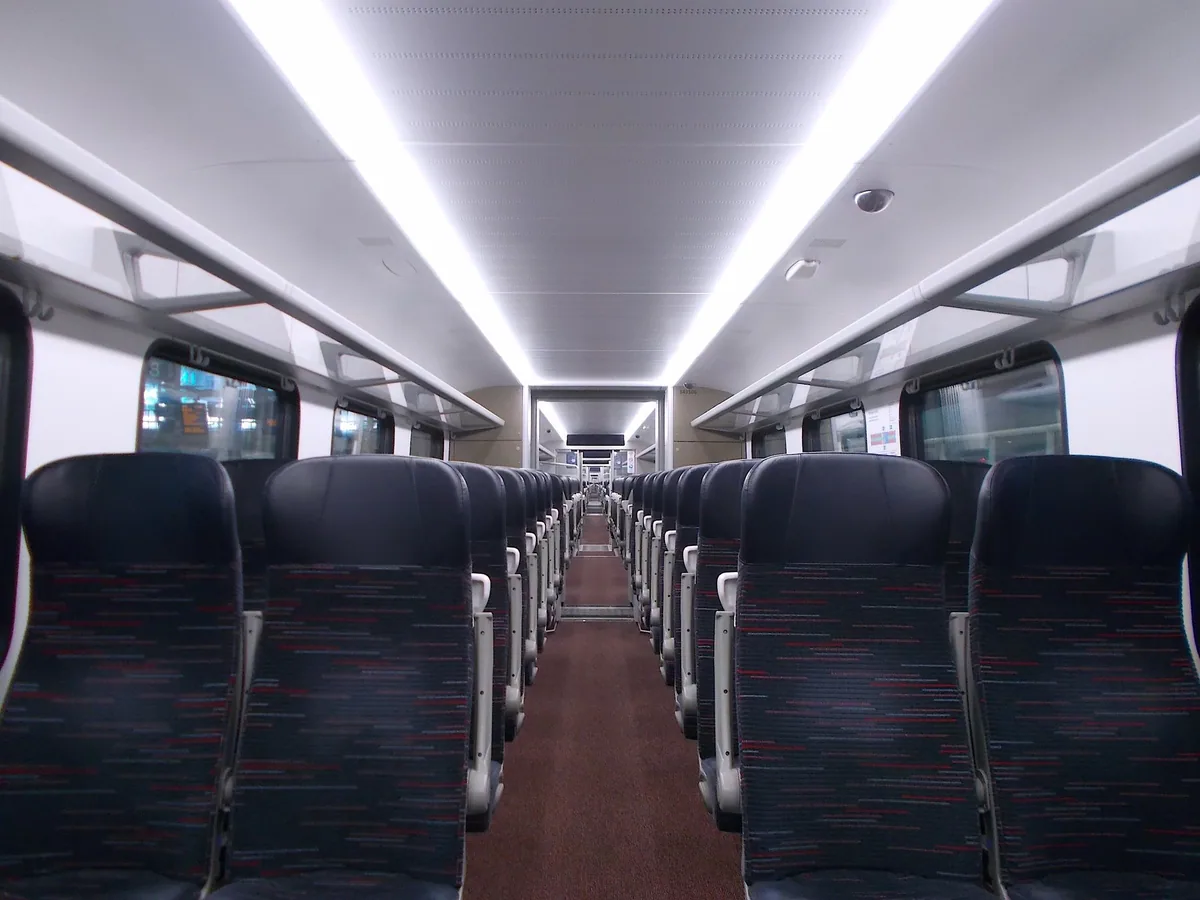 Midtgang og mørkeblå seter i en tom togvogn av typen som brukes på Stansted Express