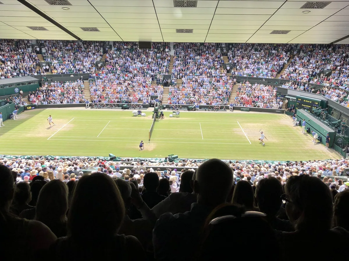 Kamp på gressbanen på Centre Court i Wimbledon, sett fra øvre tribune med fullsatte rader rundt