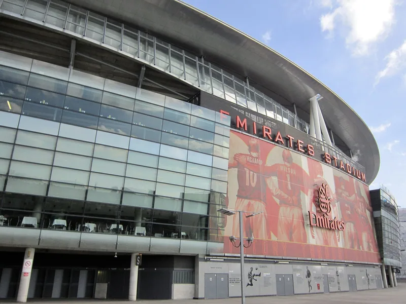 Fasaden på Emirates Stadium med glassvegger og store bilder av tidligere Arsenal-spillere