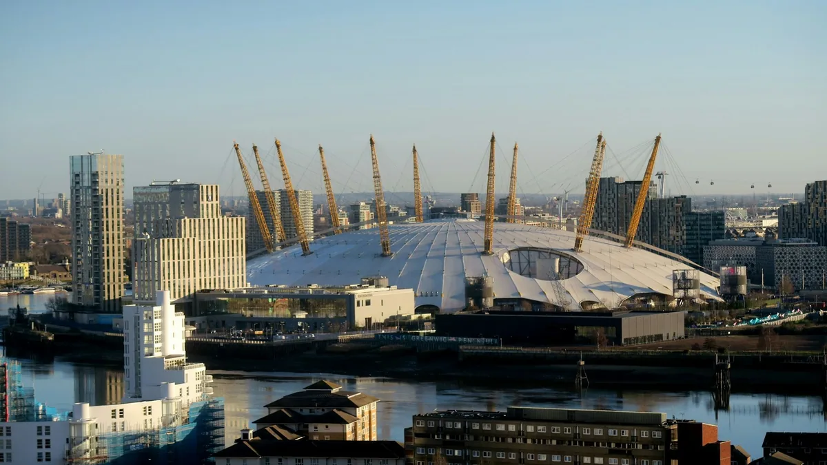 The O2 på Greenwich-halvøya med den hvite teltduken og gule master, sett over Themsen i kveldssol