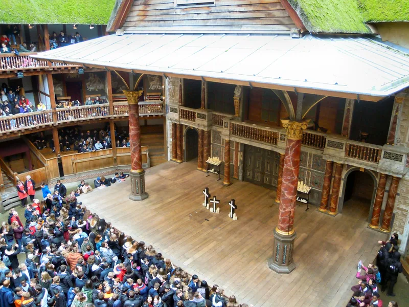 Publikum står tett i gården foran scenen i Shakespeare's Globe, sett ovenfra fra galleriet