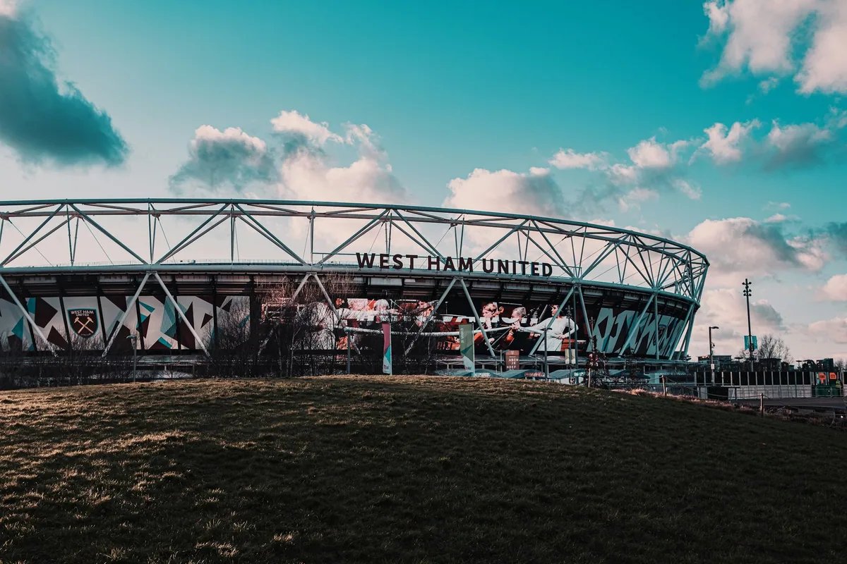 London Stadium i Stratford med West Ham United-navnet under stålkransen, sett fra en gresskledd skråning