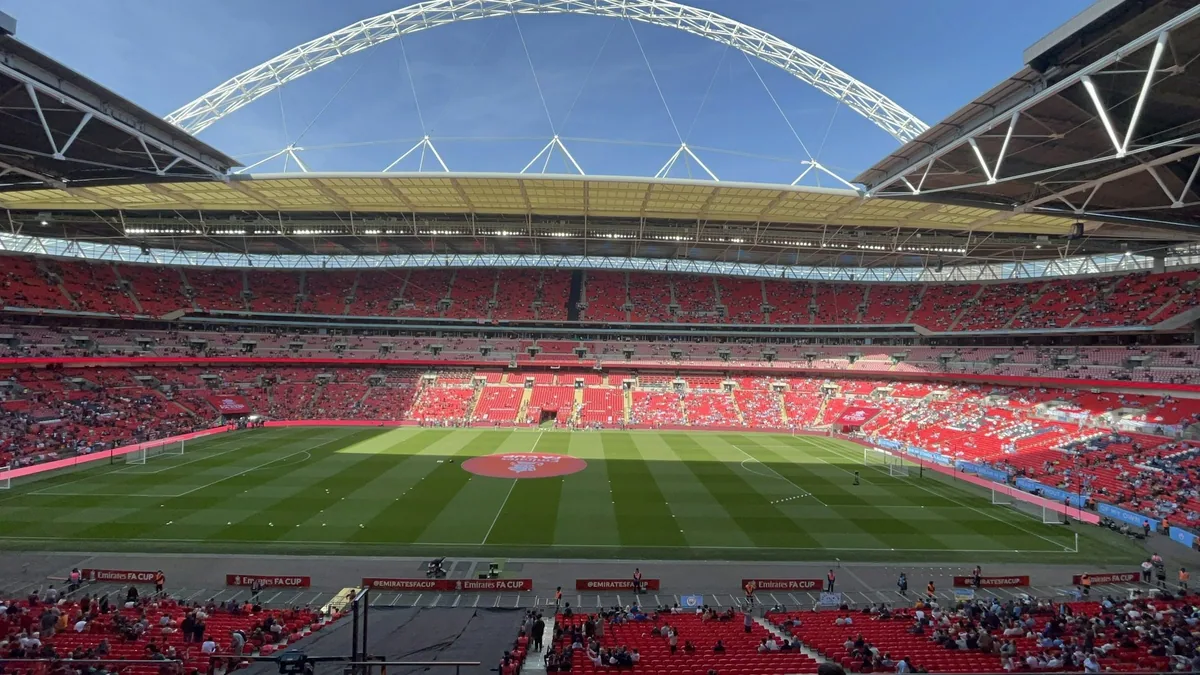 Innsiden av Wembley Stadium før en cupkamp, med røde seter, grønn bane og buen over taket