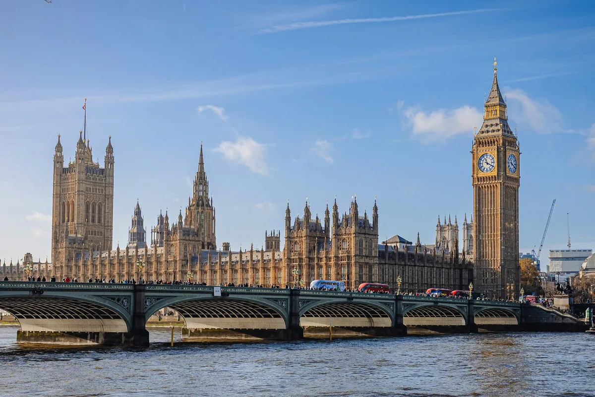 Big Ben og parlamentsbygningen i Westminster bak Westminster Bridge under blå himmel