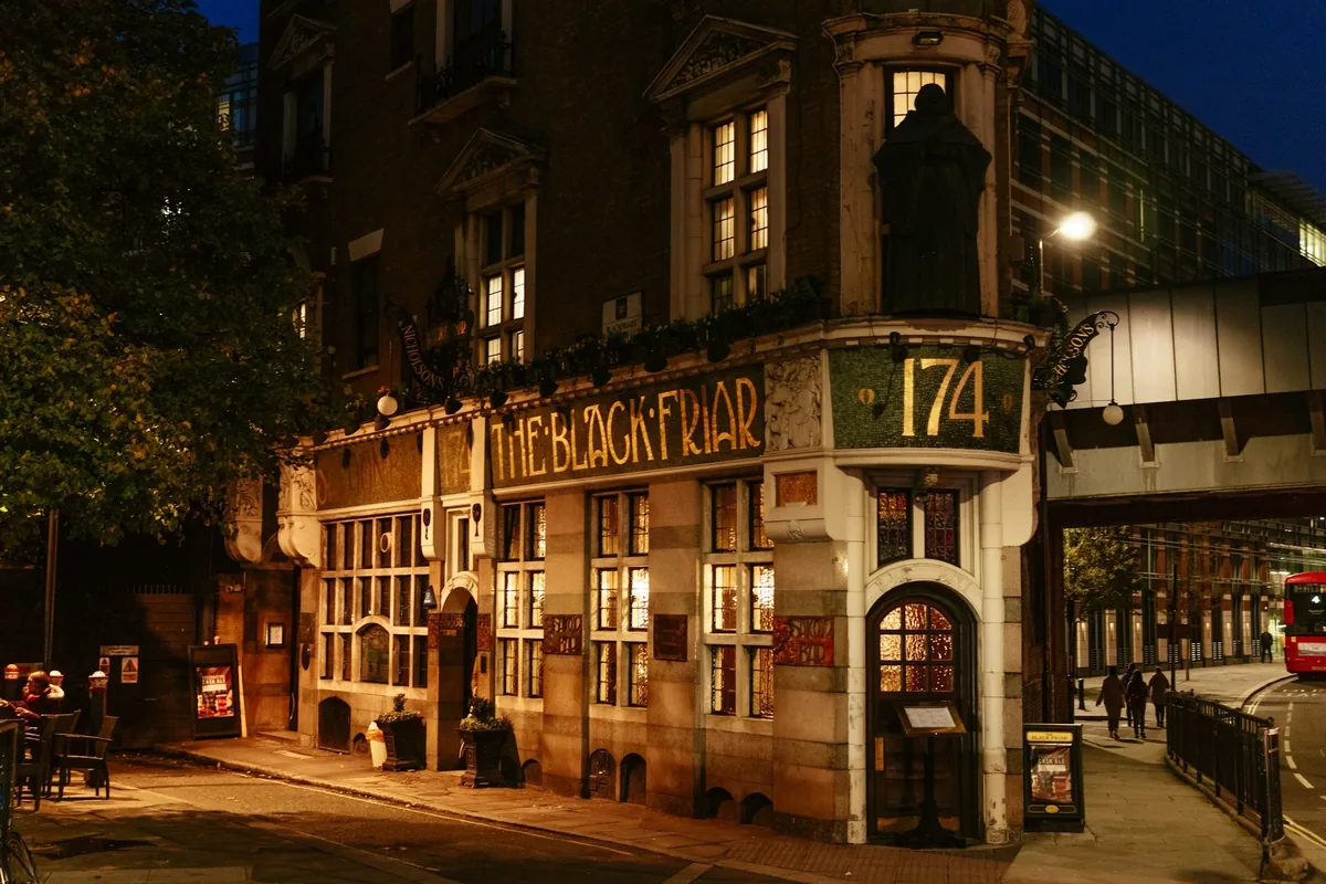 Puben The Black Friar med jugendfasade, munkestatue og opplyste vinduer en kveld i London