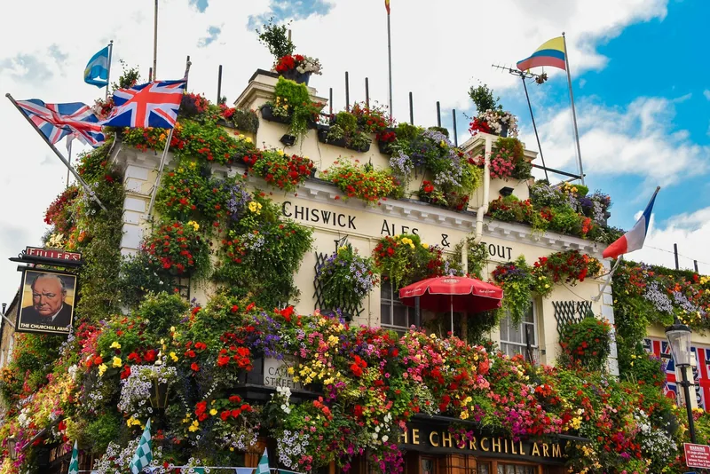 The Churchill Arms i Kensington med fasaden dekket av blomsterkasser og britiske flagg på taket