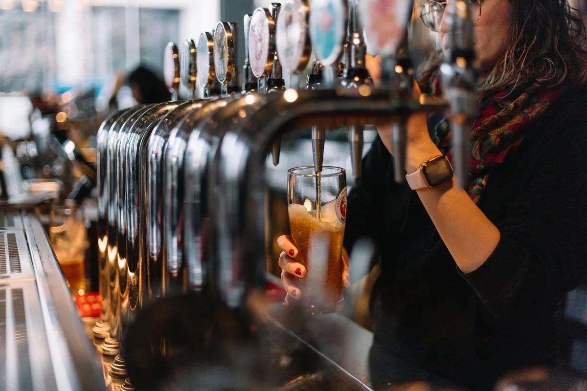 En pint fylles fra en lang rekke ølkraner i en bar i London