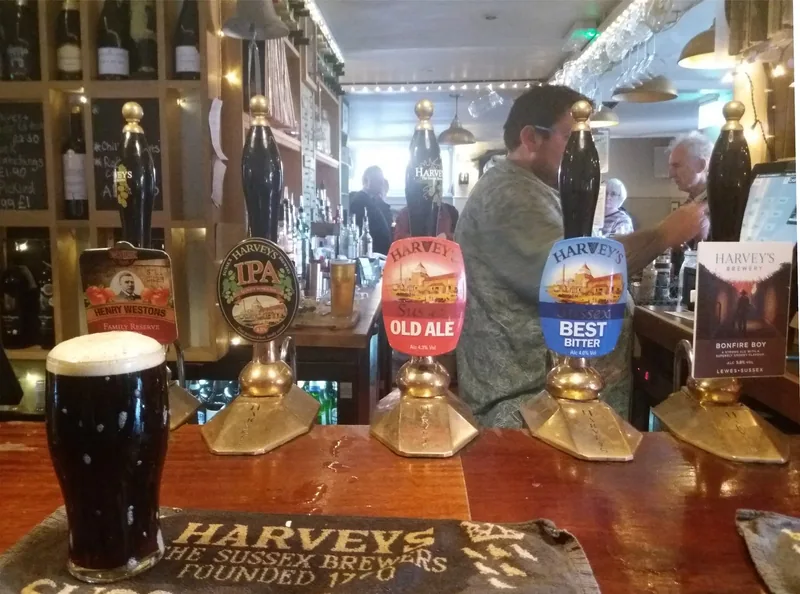 Håndpumper med skilt for bitter, old ale og IPA på en bardisk, med en pint mørk porter foran