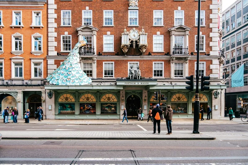 Fasaden til Fortnum & Mason på Piccadilly med en stor påfugl-dekorasjon og buede utstillingsvinduer