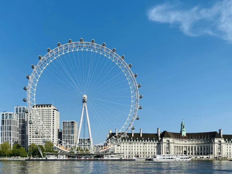 London Eye og County Hall ved Themsen under klar blå himmel