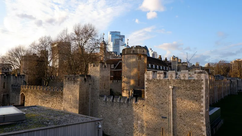 Tower of London i lav kveldssol, med nakne trær og kontorbygg i City bak murene
