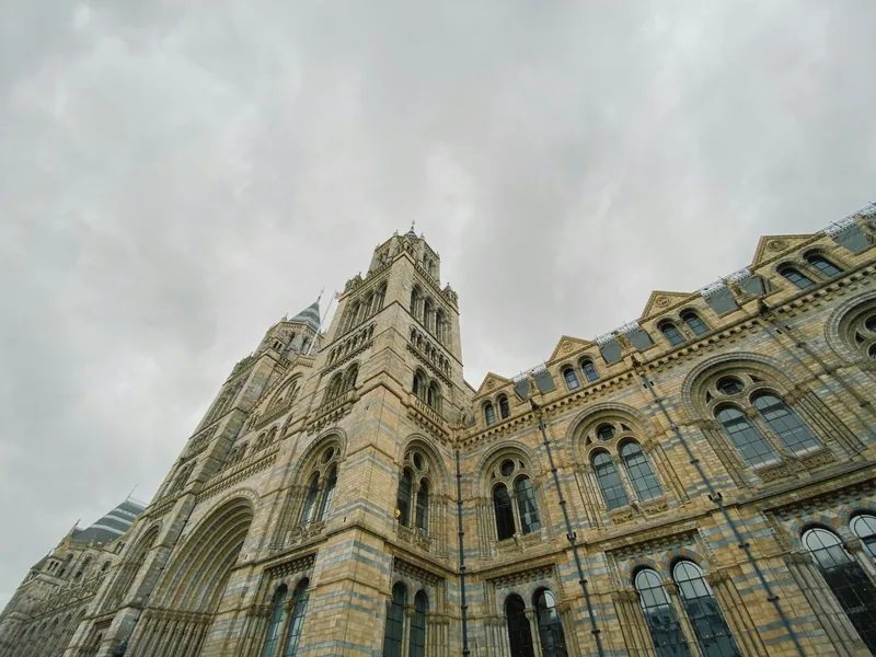 Fasaden og tårnene på Natural History Museum sett nedenfra under grå himmel