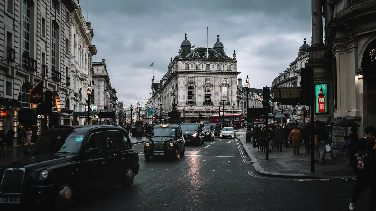 Svarte drosjer på våt gate ved Piccadilly Circus en grå regnværsdag