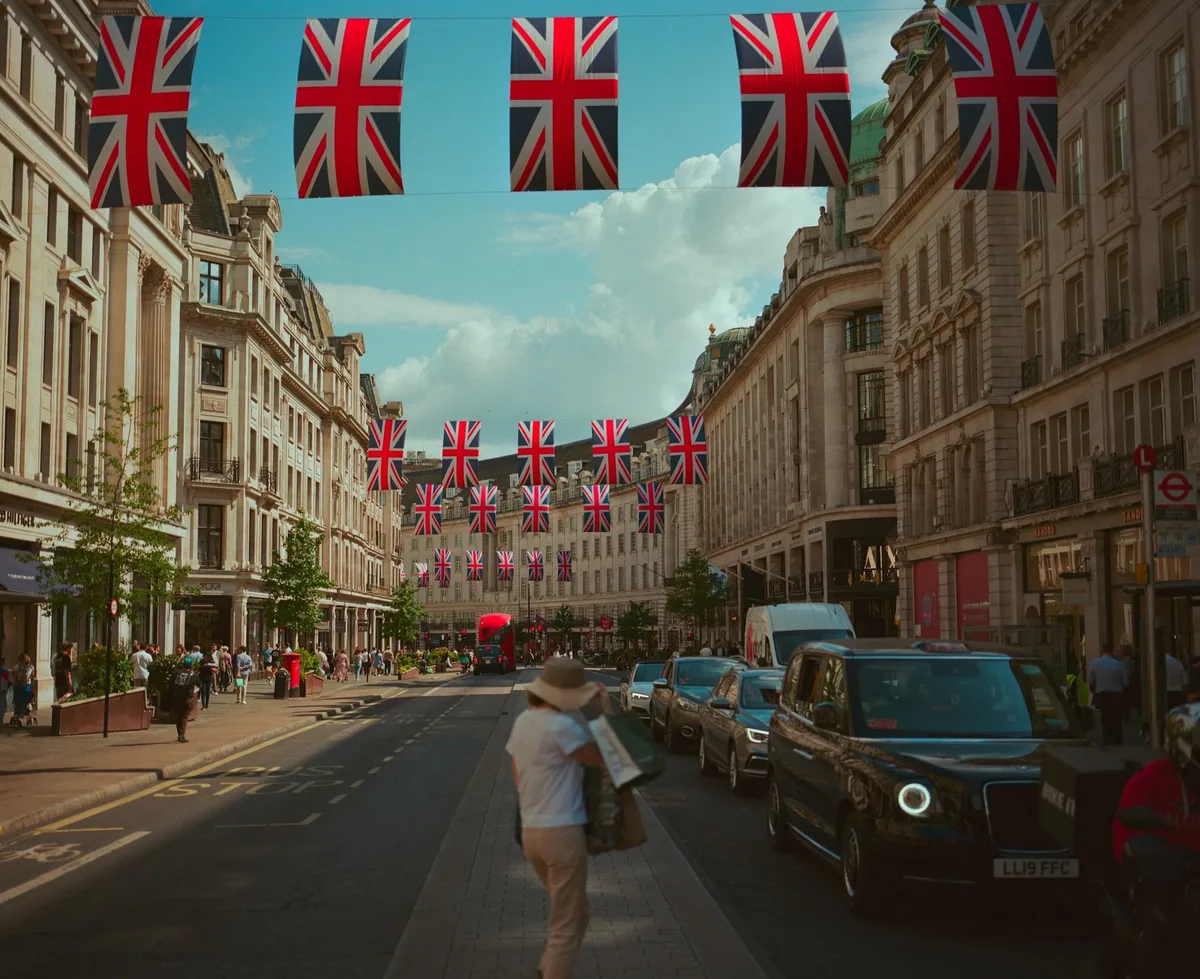 Regent Street med rekker av Union Jack-flagg over gaten, butikkfasader og en rød buss i det fjerne