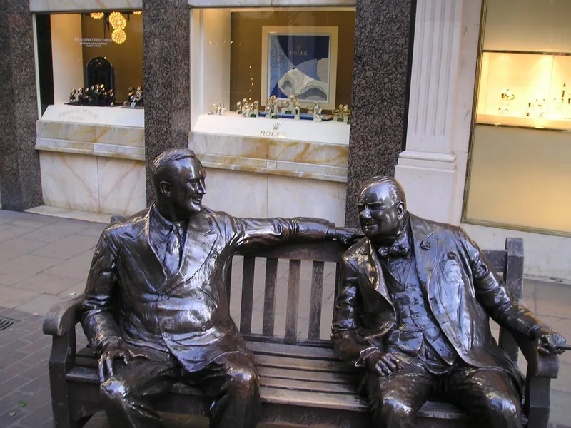 Bronseskulpturen «Allies» av Roosevelt og Churchill på en benk foran et klokkevindu i New Bond Street