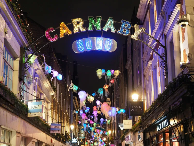 Carnaby Street om kvelden med den opplyste Carnaby-buen og lysende maneter hengende over gaten