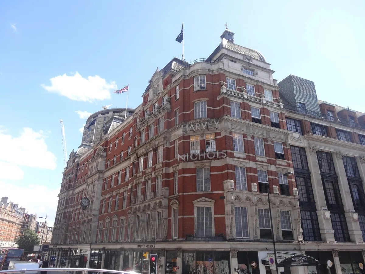 Harvey Nichols' viktorianske fasade i rød murstein og lys stein på hjørnet i Knightsbridge, med flagg på taket