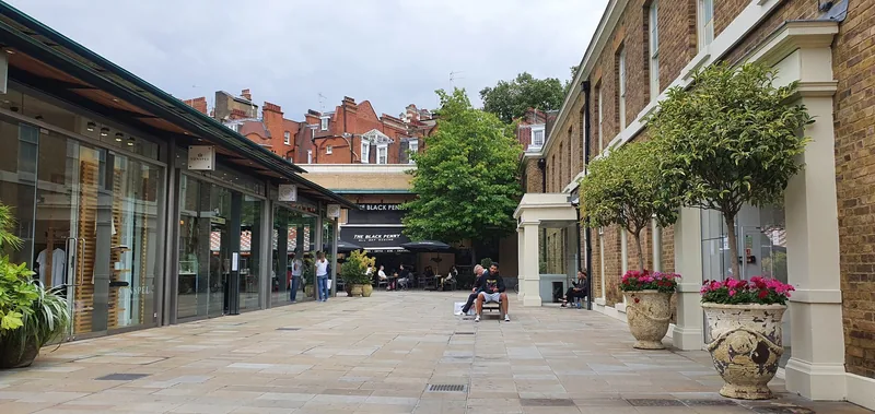 Bilfri gågate med butikker, blomsterkrukker og et tre på Duke of York Square ved King's Road