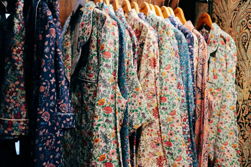 Rad av skjorter i blomstrete stoffer på trekleshengere hos varehuset Liberty