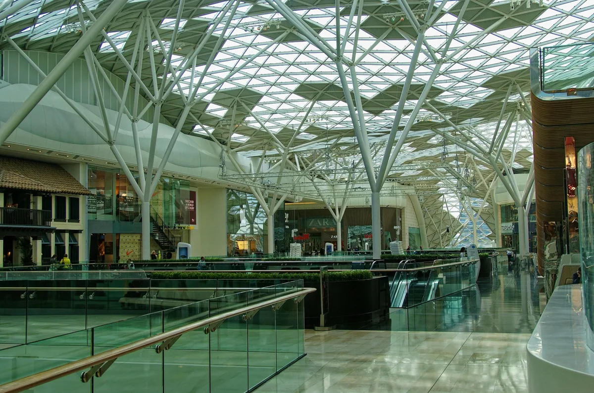 Glasstaket med hvite stålsøyler over butikkgatene inne i Westfield London ved Shepherd's Bush