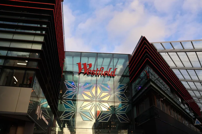 Inngangen til Westfield Stratford City med rød logo over en glassfasade mellom to moderne bygg
